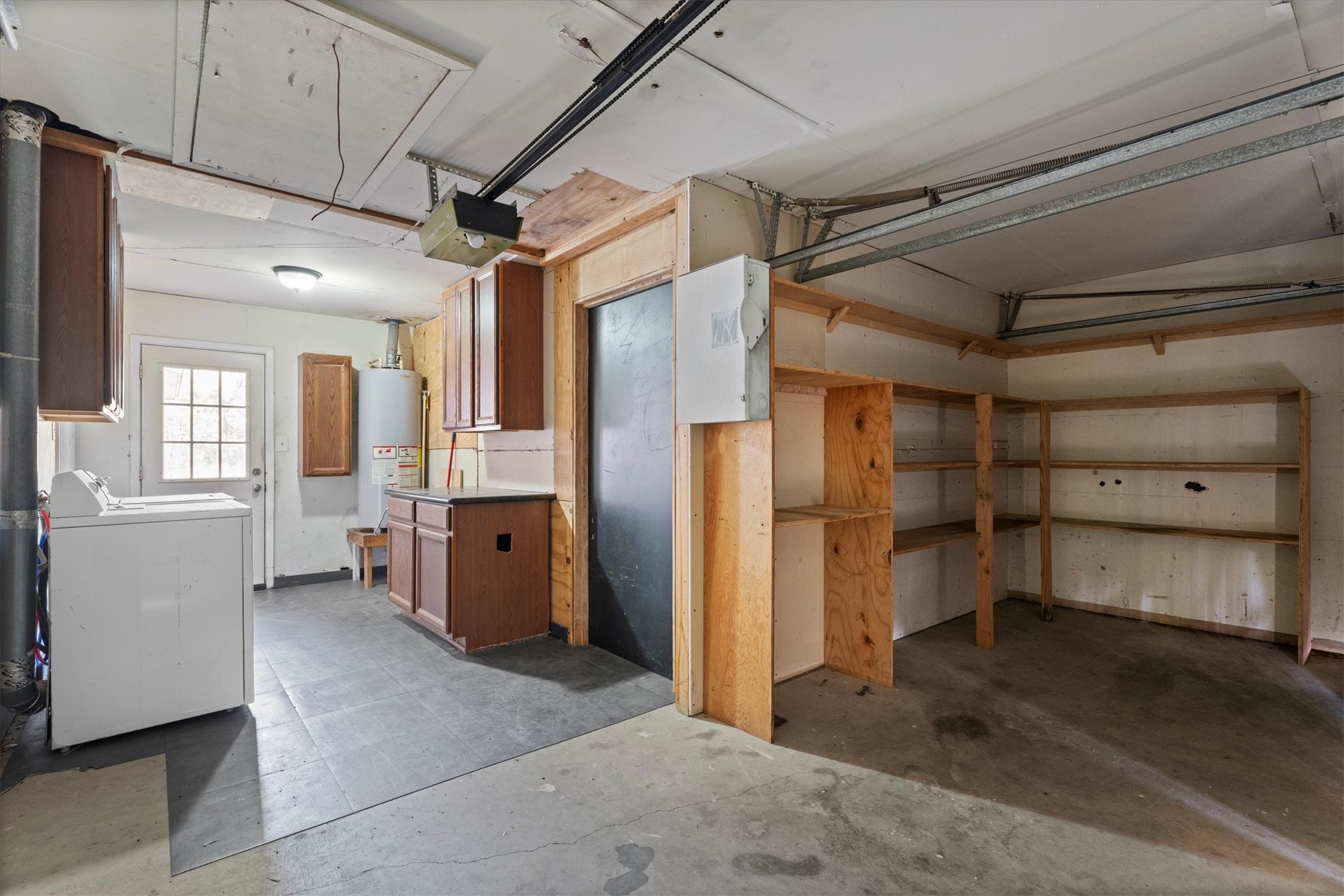 104 Anna Street Tomball, TX 77375 - Photo 16 of 32 The garage was coverted into storage and utility areas. The water heater is located in the garage. It's well-lit through a door that gives access to the backyard. Shelving, cabinets, washer and dryer are included.