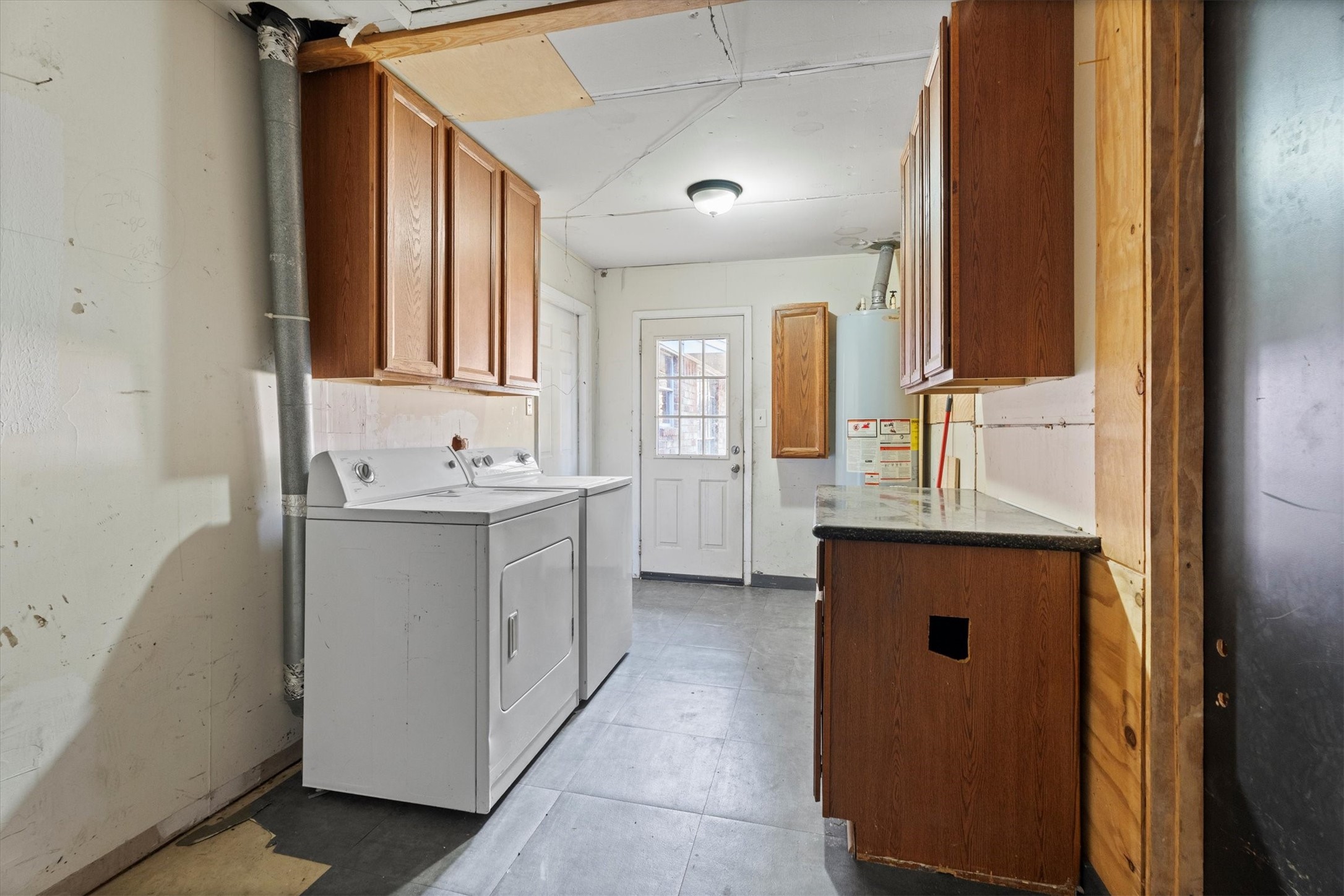 104 Anna Street Tomball, TX 77375 - Photo 18 of 32 This part of the garage serves as the laundry/utility room with a washer and dryer (included), overhead cabinets, and a countertop.