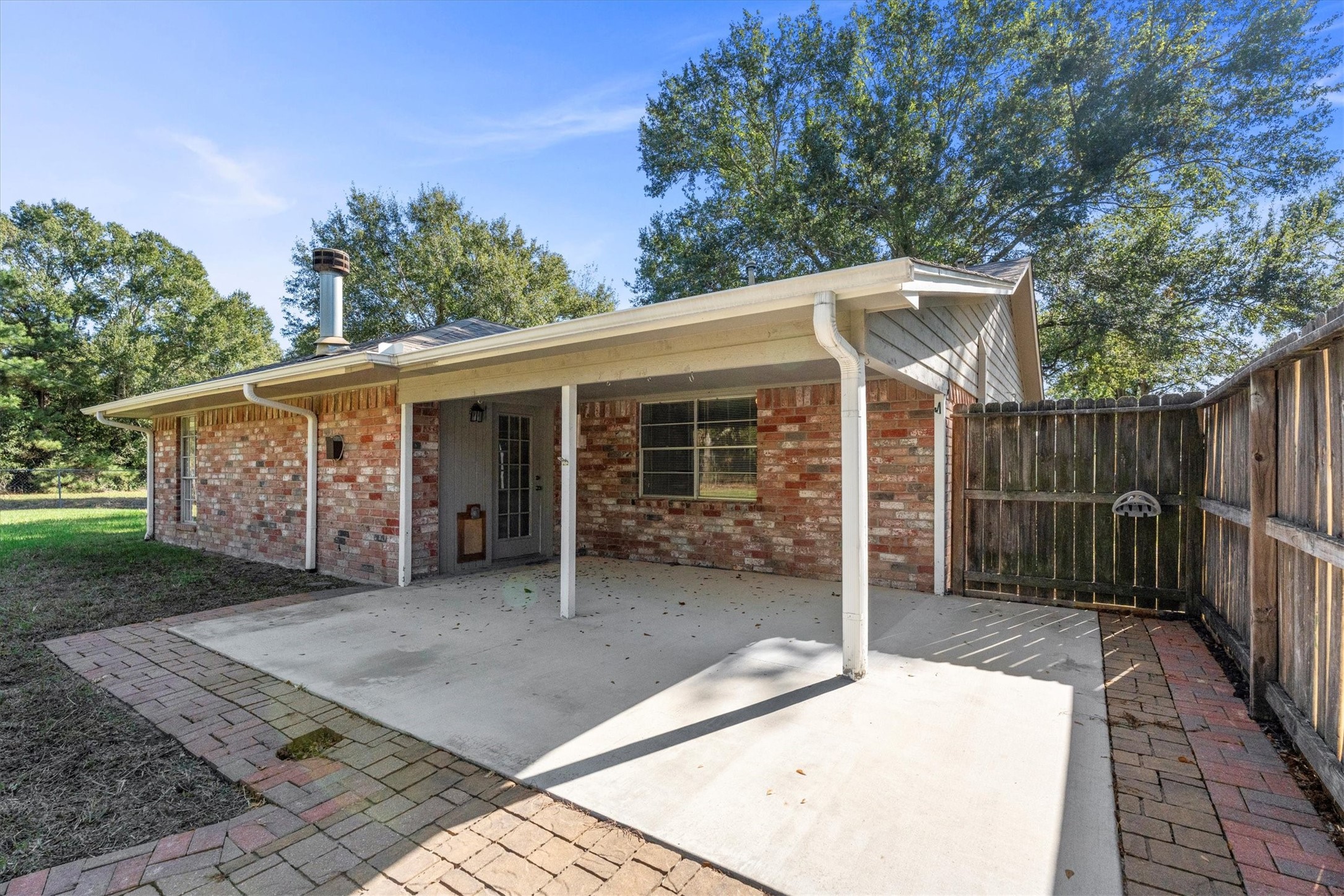 104 Anna Street Tomball, TX 77375 - Photo 19 of 32 Partially covered back patio, ideal for outdoor relaxation. The fenced yard provides privacy, and mature trees offer a pleasant backdrop. Perfect for enjoying peaceful surroundings.