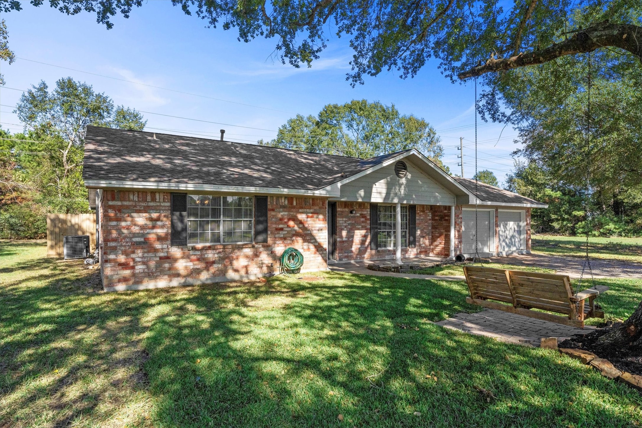 104 Anna Street Tomball, TX 77375 - Photo 2 of 32 Charming brick home with a cozy front porch and spacious yard (almost 1/3 acre). Features mature trees providing shade and a wooden swing for relaxation. Ideal for enjoying outdoor living.