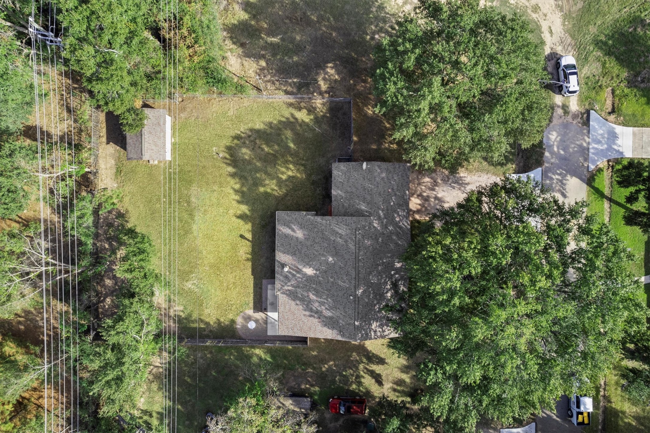 104 Anna Street Tomball, TX 77375 - Photo 26 of 32 This aerial view showcases a spacious property with a single-story home surrounded by lush trees. The large backyard offers ample space, and there’s a driveway leading to the house. The setting provides privacy and a serene atmosphere.