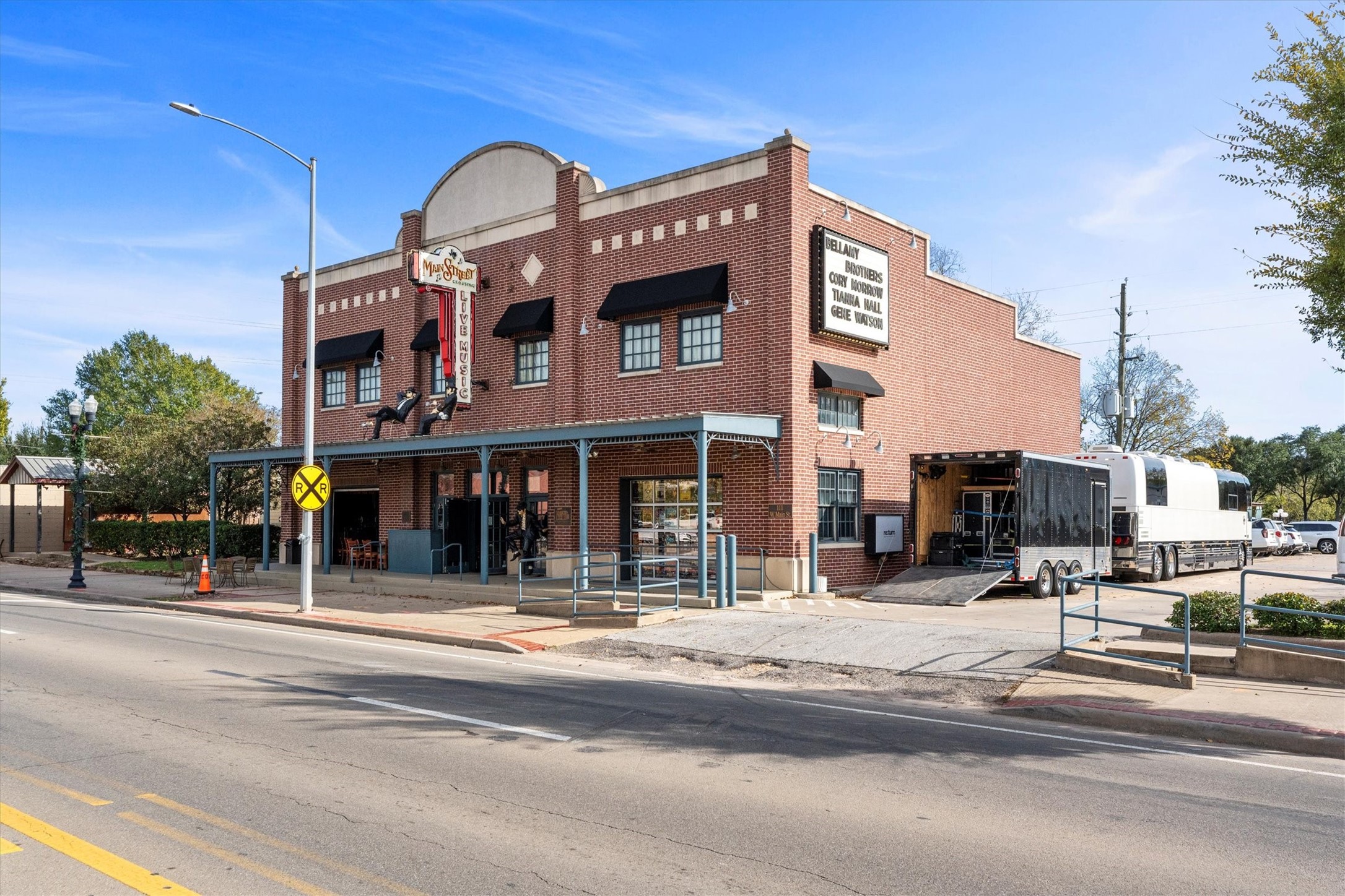 104 Anna Street Tomball, TX 77375 - Photo 29 of 32 This Main Street Venue is home to live music events. It's adjacent to a railroad crossing, adding a quaint, small-town feel. The area appears to have ample parking and a mix of commercial activity, suggesting a lively neighborhood.