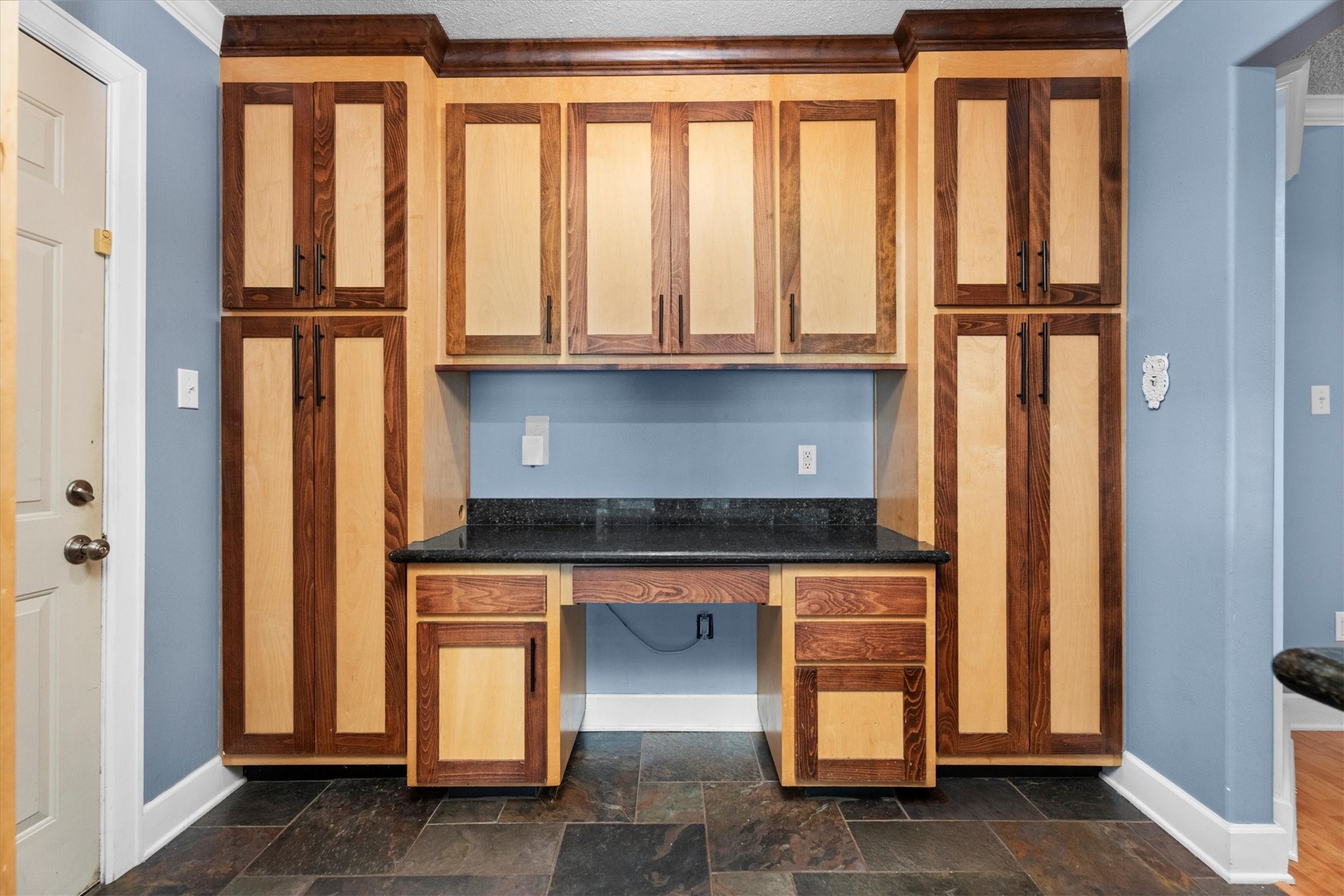104 Anna Street Tomball, TX 77375 - Photo 7 of 32 The custom two-tone wood cabinetry with black granite countertop extends into a nook on the opposite end of the kitchen from the dining area providing a desk and plenty of pantry space.