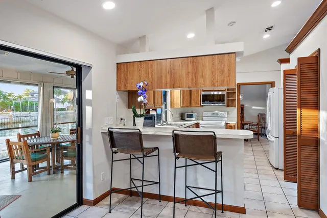a kitchen with stainless steel appliances kitchen island granite countertop a dining table chairs stove a refrigerator and a view of living room