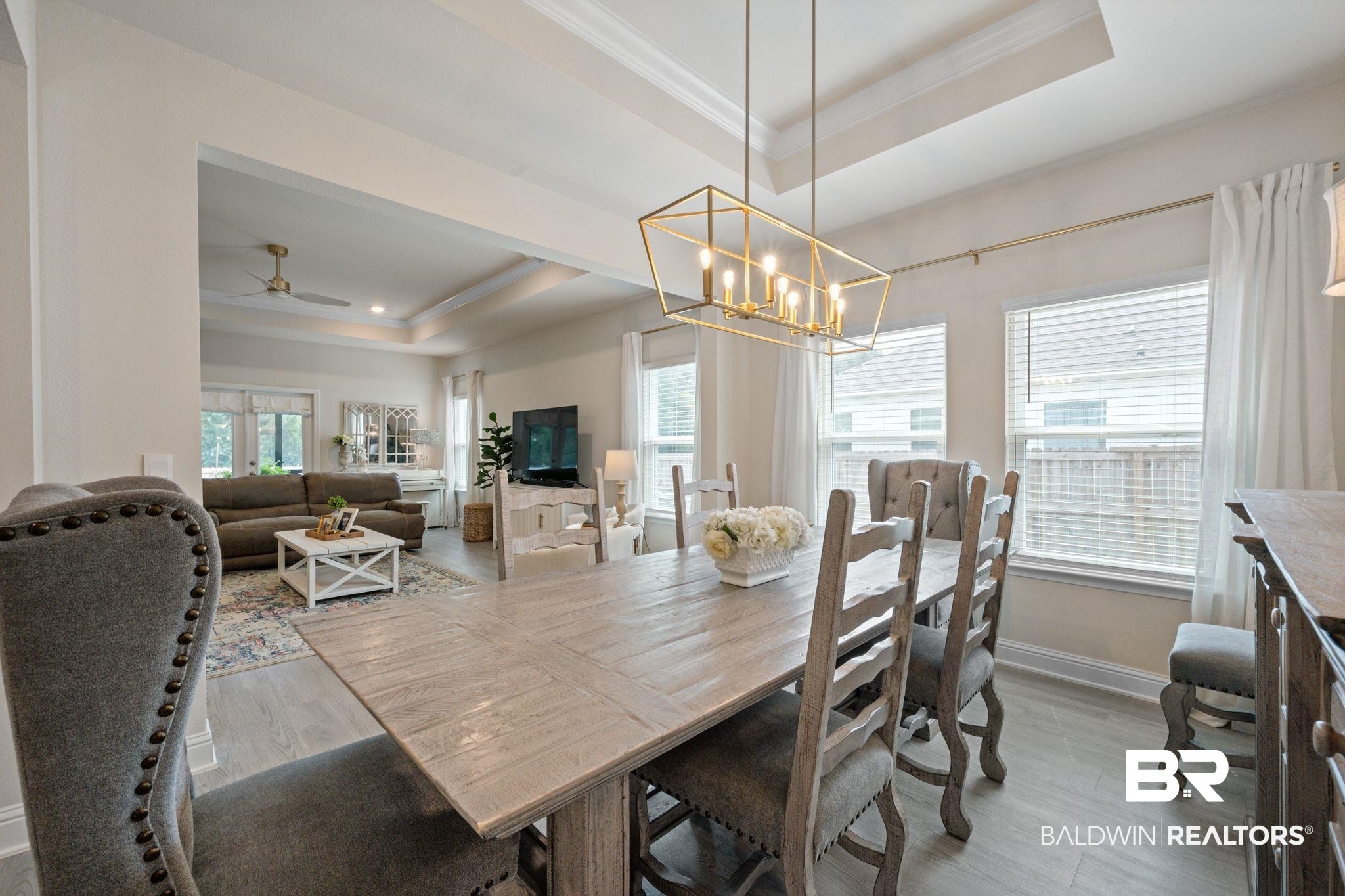 681 Calibre Street Fairhope, AL 36532 - Photo 14 of 56 Dining area featuring a raised ceiling, ceiling fan with notable chandelier, and light wood-type flooring