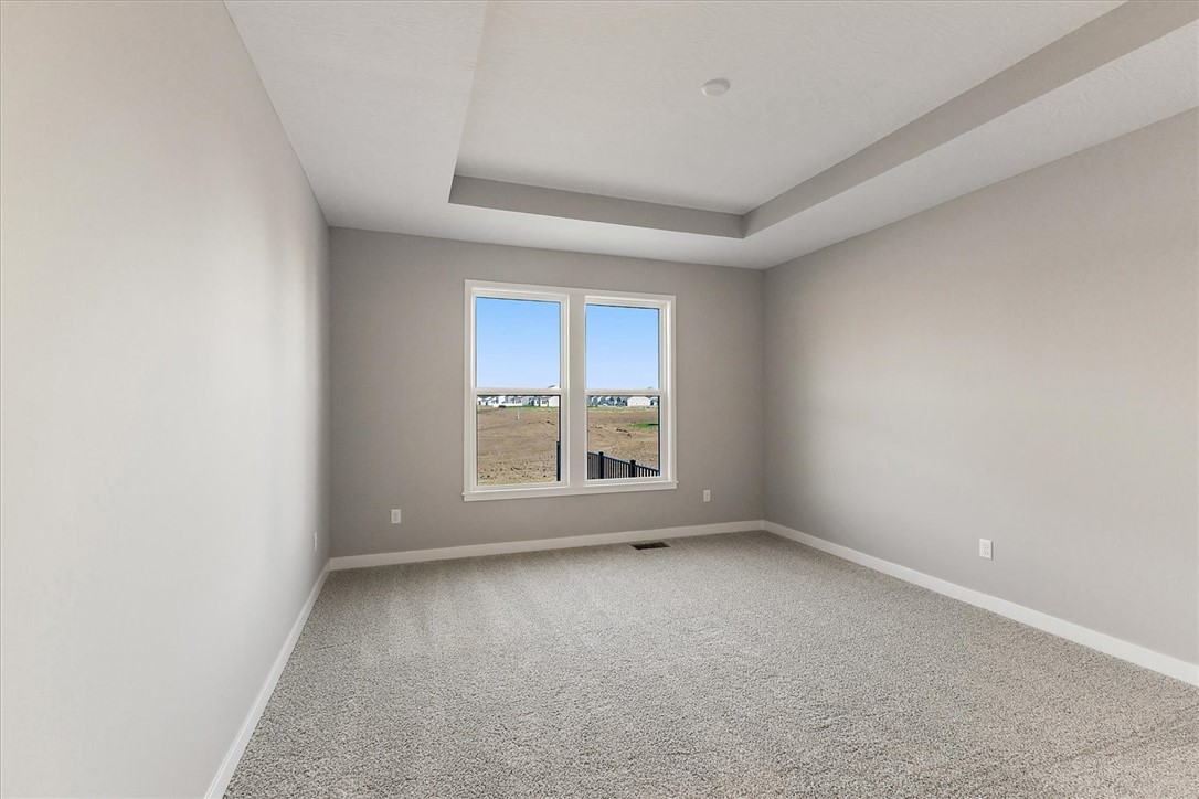 407 South Landon Lane Springfield, OH 45502 - Photo 9 of 30 This primary bedroom features a modern tray ceiling, large windows, and soft carpeting, creating a comfortable and elegant personal retreat.