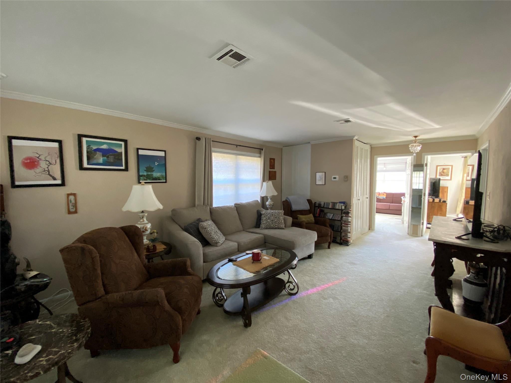 274 Berwick Court, Unit A Ridge, NY 11961 - Photo 12 of 31 Carpeted living room with healthy amount of natural light and crown molding