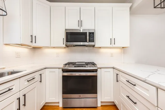 a kitchen with granite countertop white cabinets and stainless steel appliances