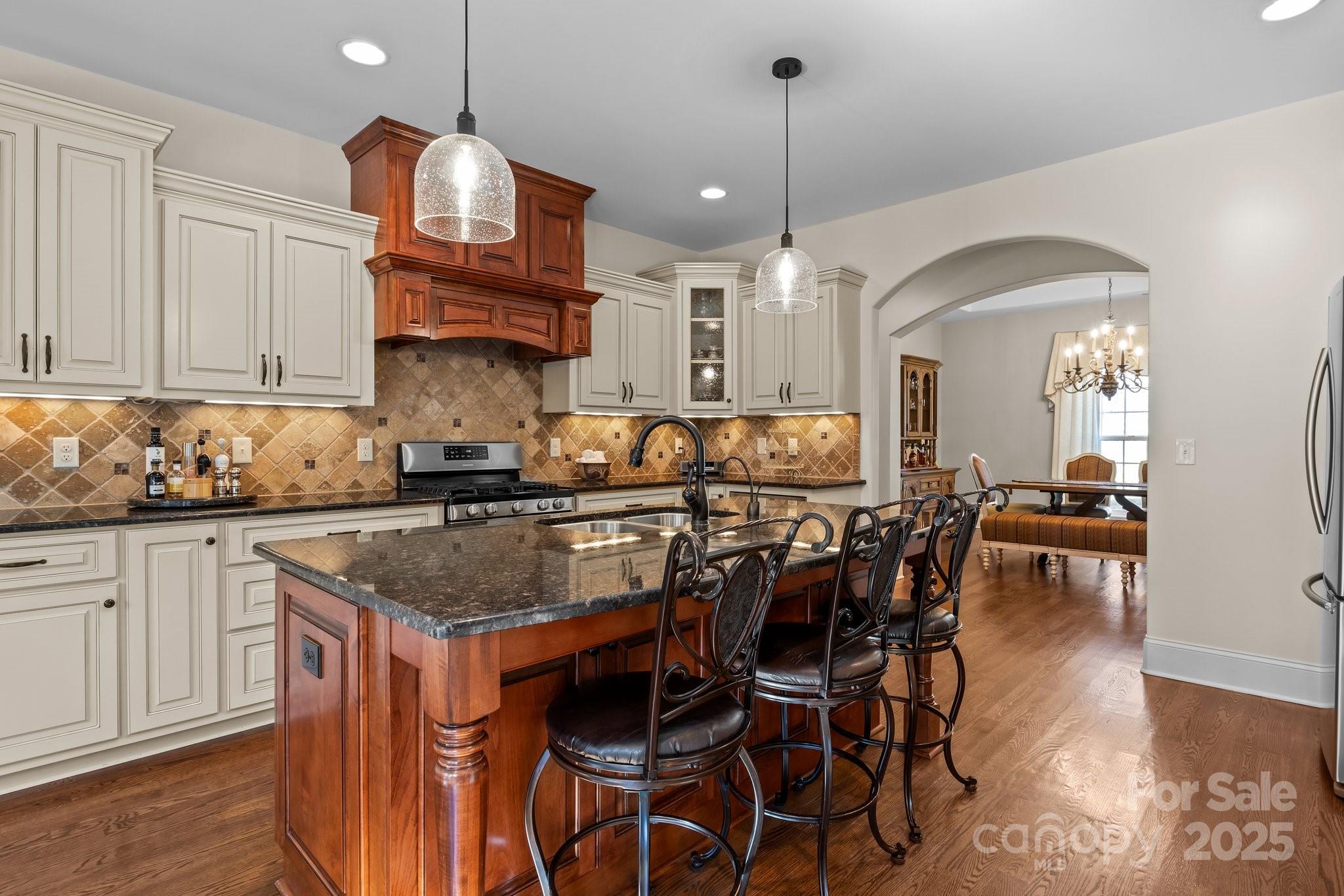 574 Barber Loop Mooresville, NC 28117 - Photo 8 of 34 a kitchen with stainless steel appliances granite countertop a stove top oven a sink a dining table and chairs with wooden floor