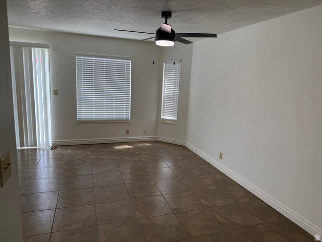 747 Hanover Drive Orem, UT 84058 - Photo 8 of 30 Empty room with a textured ceiling, a ceiling fan, and dark tile patterned floors
