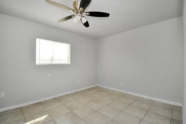 an empty room with a window and a fan