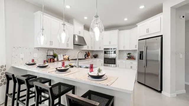 a kitchen with stainless steel appliances granite countertop white cabinets sink and a refrigerator