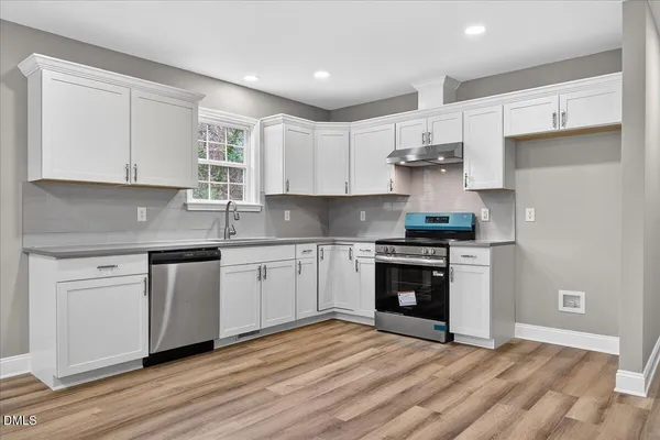 a kitchen with stainless steel appliances granite countertop a stove and white cabinets