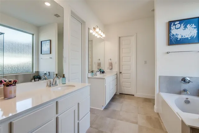 a bathroom with a tub a sink double vanity and a shower
