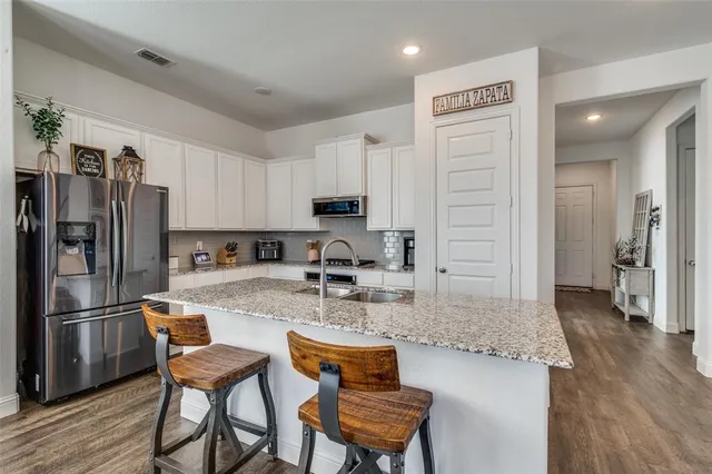 a kitchen with stainless steel appliances granite countertop a refrigerator and a stove top oven