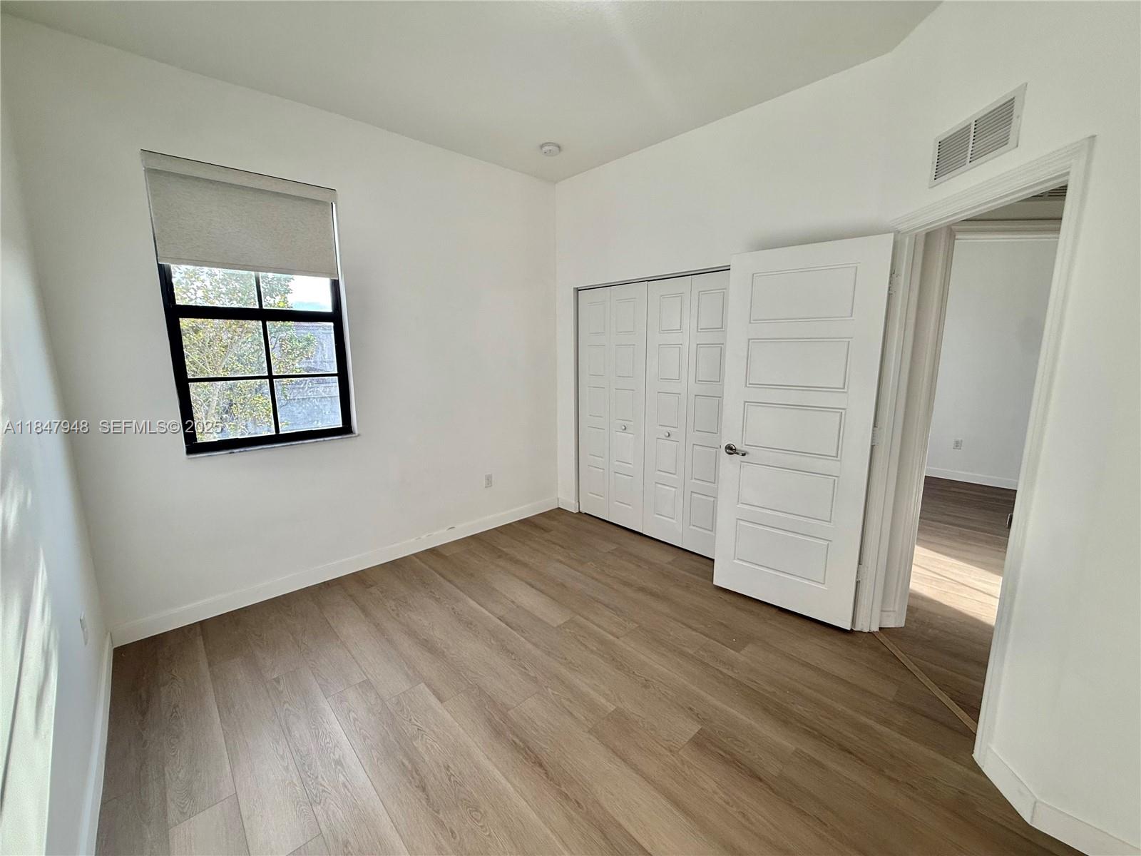 673 Northeast 191st Street Miami, FL 33179 - Photo 15 of 25 an empty room with wooden floor and cabinet