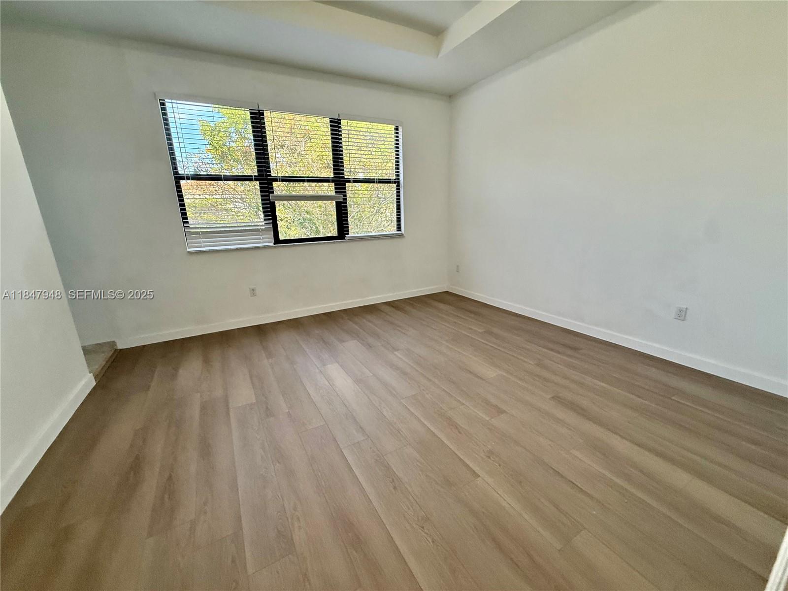 673 Northeast 191st Street Miami, FL 33179 - Photo 16 of 25 an empty room with wooden floor and windows