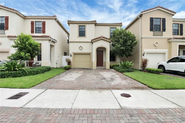 a view of a white house with a yard and plants