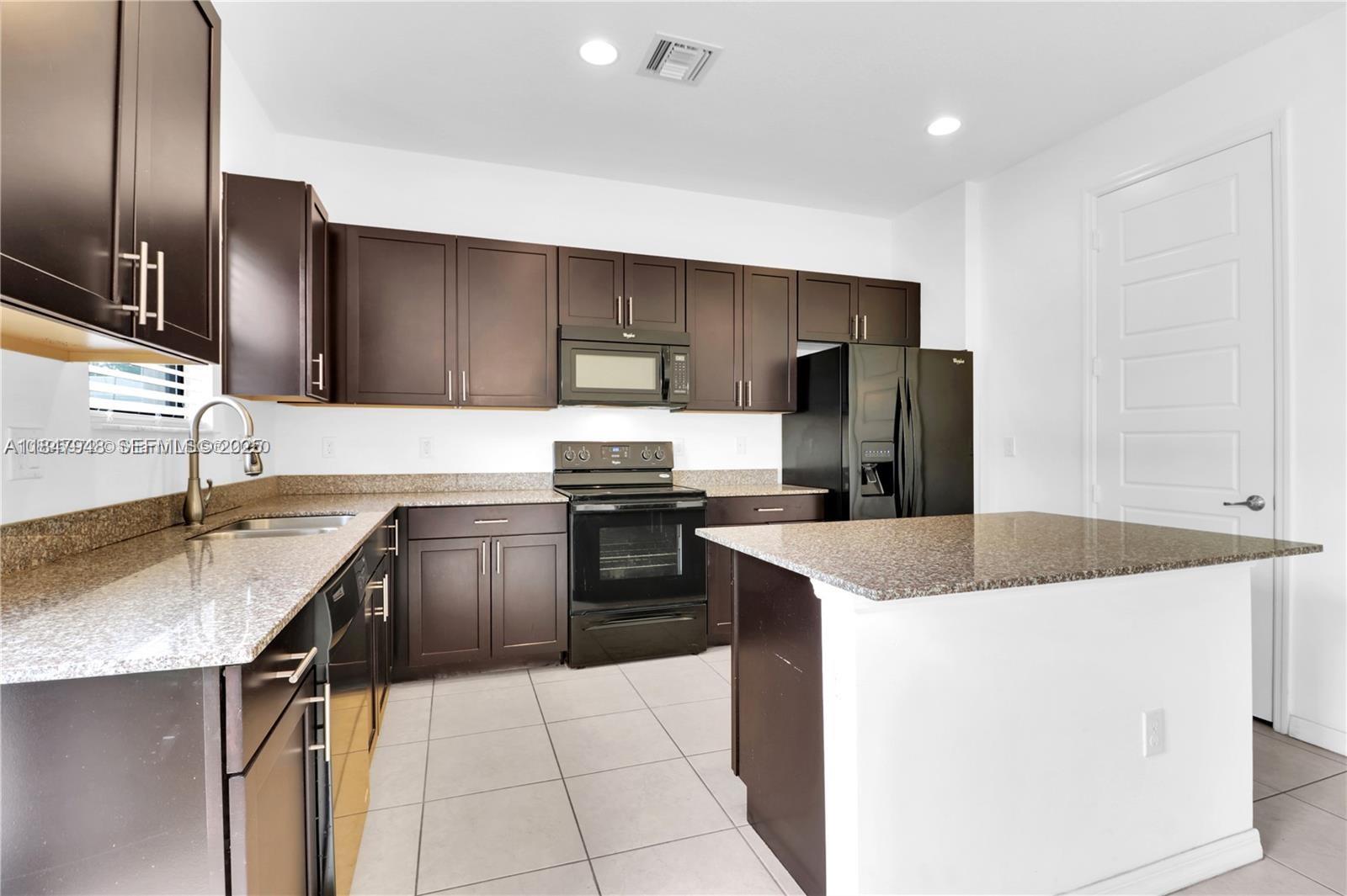 673 Northeast 191st Street Miami, FL 33179 - Photo 8 of 25 a kitchen with a sink a stove top oven and refrigerator