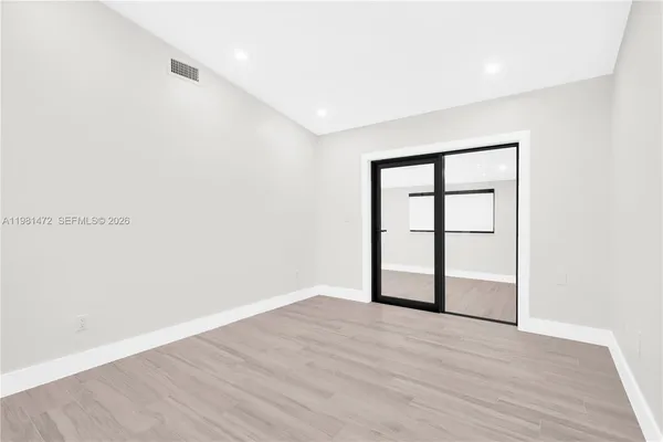 an empty room with wooden floor and windows