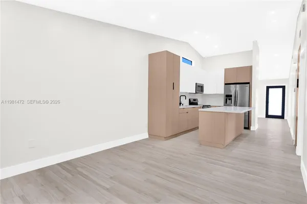 a view of a kitchen with a sink a refrigerator a microwave and cabinets