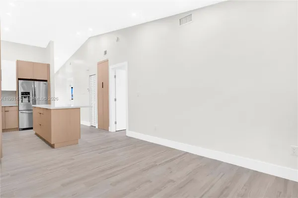 a view of a kitchen with wooden floor and a refrigerator