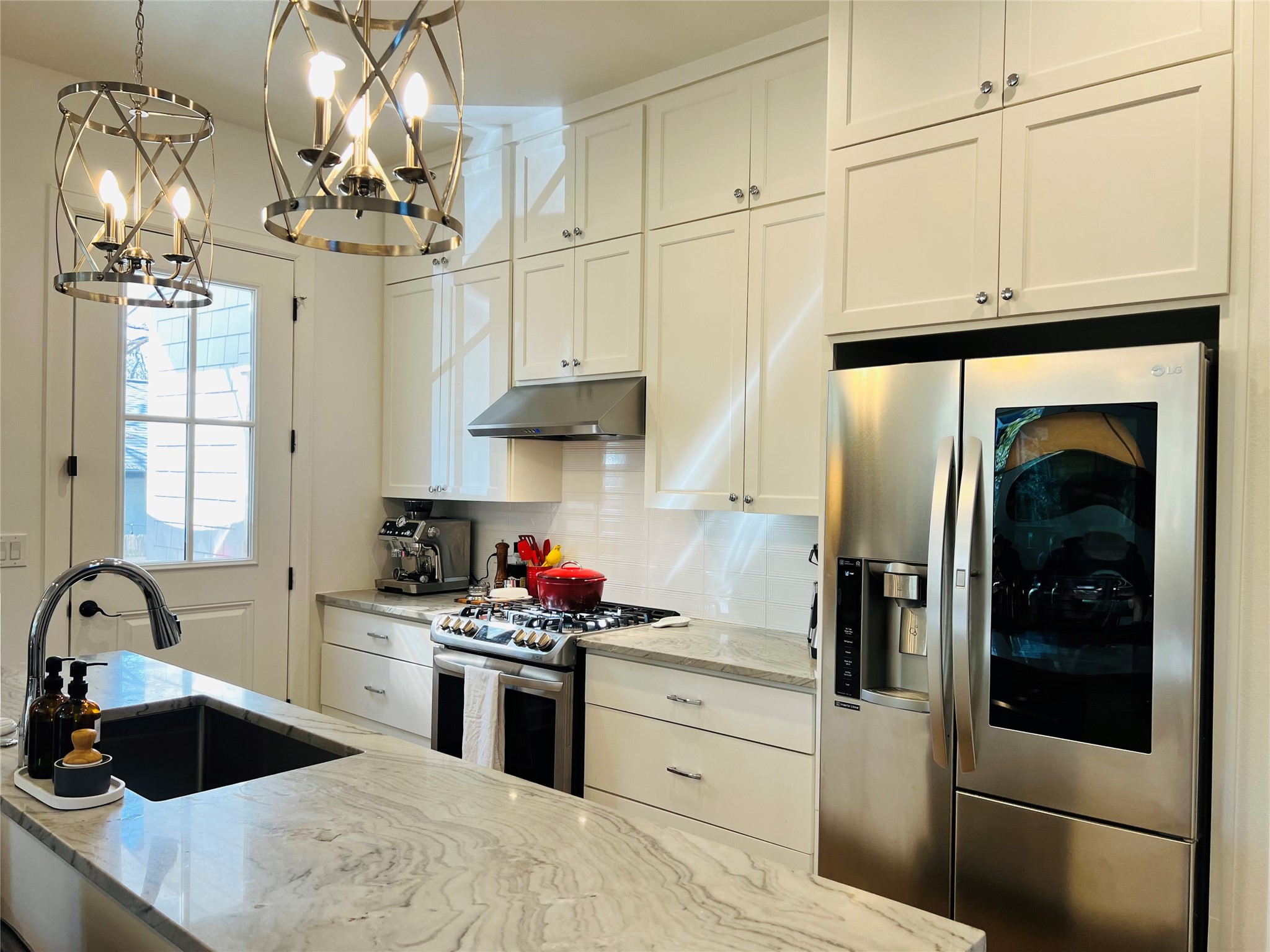 4704 Duval Street Austin, TX 78751 - Photo 22 of 29 a kitchen with stainless steel appliances kitchen island granite countertop a refrigerator a sink dishwasher and white cabinets next to a window
