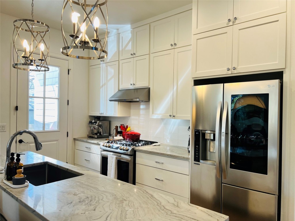 4704 Duval Street Austin, TX 78751 - Photo 22 of 29 Kitchen featuring decorative backsplash, light stone countertops, stainless steel appliances, under cabinet range hood, and a sink