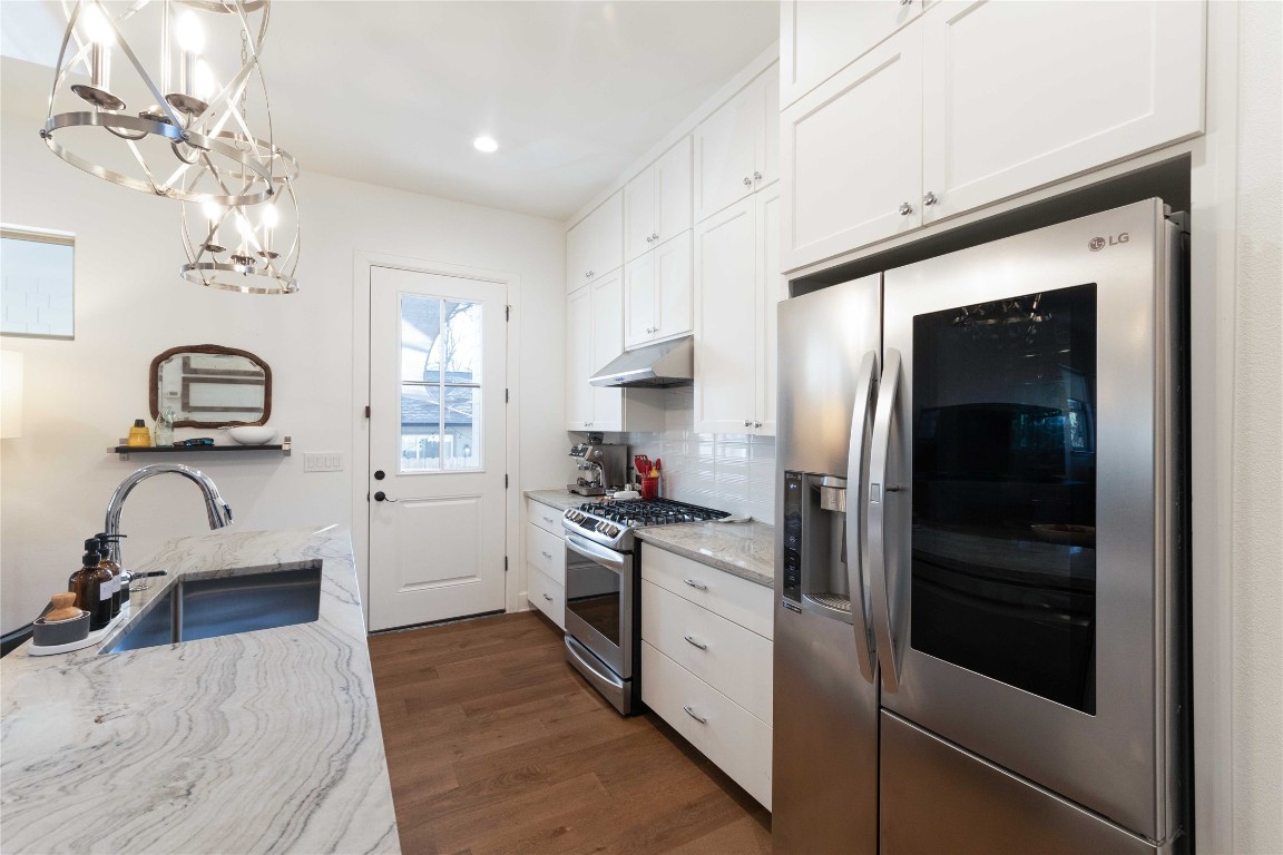 4704 Duval Street Austin, TX 78751 - Photo 8 of 29 Kitchen with dark wood-style flooring, stainless steel appliances, tasteful backsplash, white cabinets, and a sink