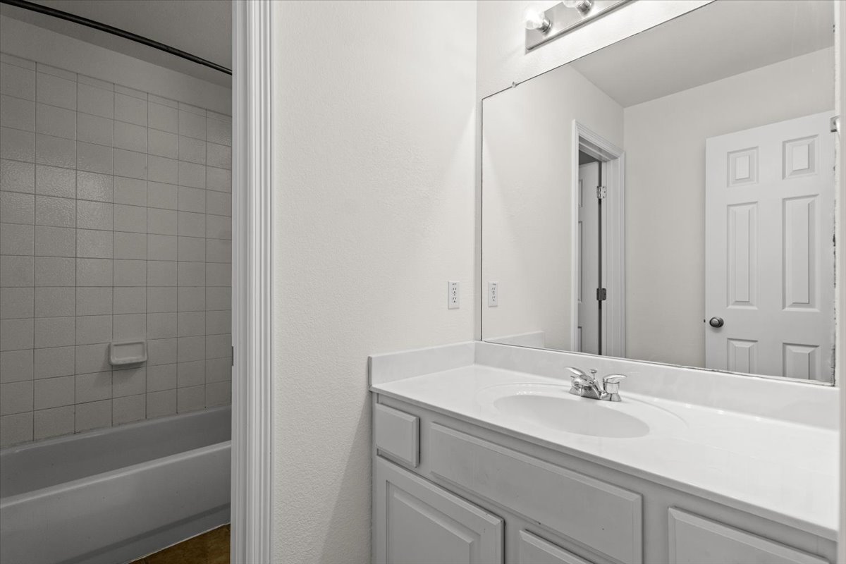 2304 Village View Loop Pflugerville, TX 78660 - Photo 37 of 40 A well-appointed bathroom offers a crisp white vanity and a practical tub with tiled surround.