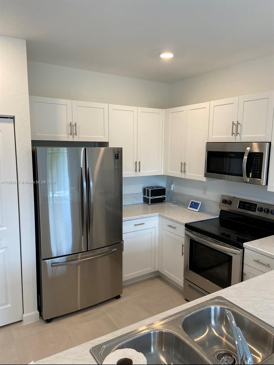 18107 Southwest 147th Court Miami, FL 33196 - Photo 6 of 25 a kitchen with stainless steel appliances granite countertop a refrigerator a stove a sink and white cabinets