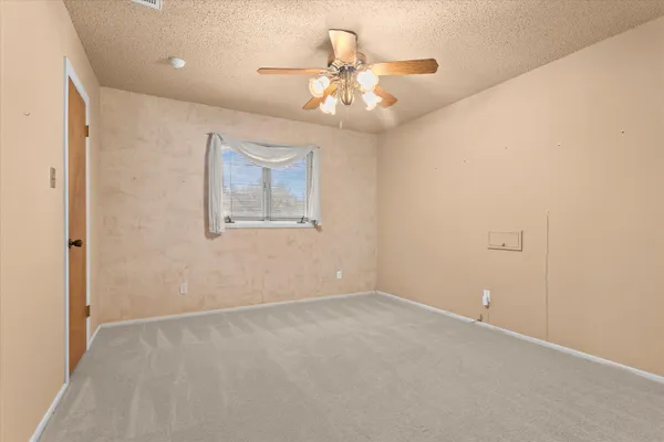 an empty room with a chandelier fan and a ceiling fan