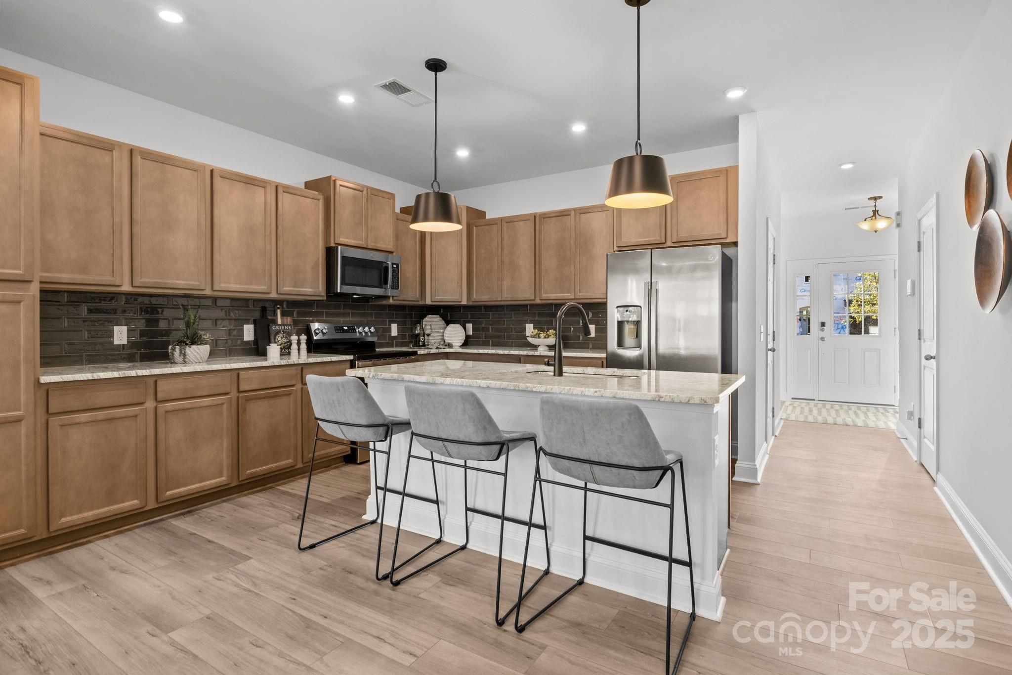 7716 Ethora Way, Unit 2 Charlotte, NC 28216 - Photo 4 of 30 a kitchen with kitchen island granite countertop a stove a sink a center island a refrigerator and a wooden cabinets