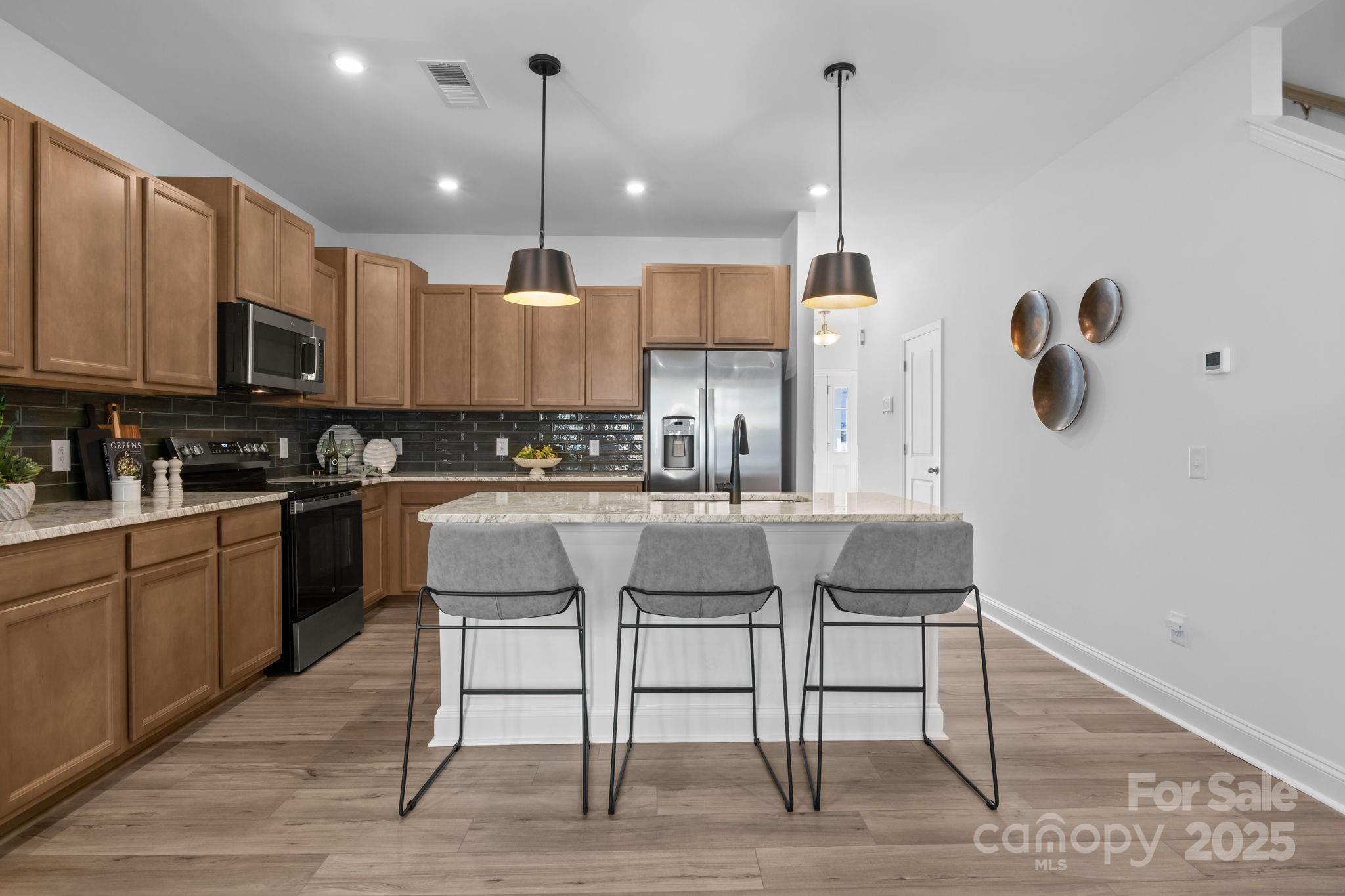 7716 Ethora Way, Unit 2 Charlotte, NC 28216 - Photo 8 of 30 a kitchen with stainless steel appliances granite countertop a kitchen island a stove a sink dishwasher and white cabinets with wooden floor