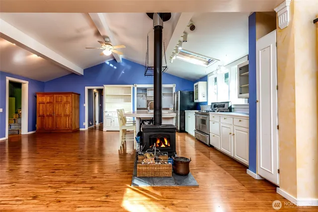 a open kitchen with stainless steel appliances granite countertop a sink dishwasher and a dining table with wooden floor