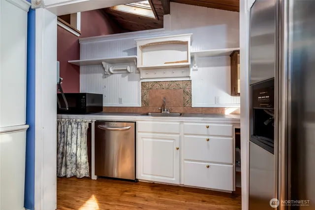 a kitchen with stainless steel appliances granite countertop a refrigerator a stove and a microwave oven with wooden floor