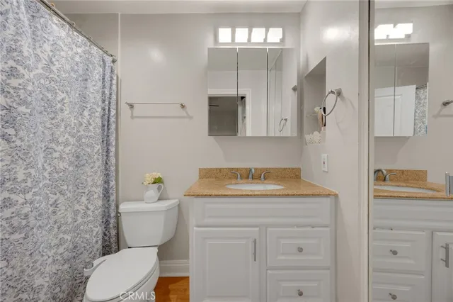 a bathroom with a granite countertop sink mirror vanity and toilet