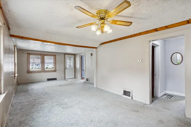 an empty room with windows and fan