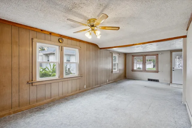 a view of an empty room with window and chandelier fan