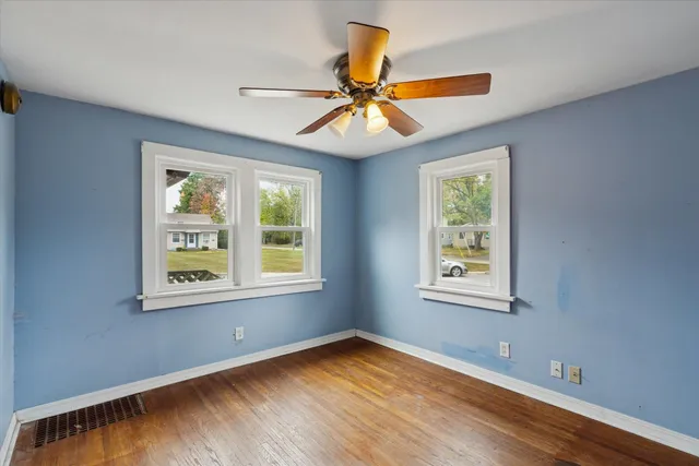 a view of an empty room with window and wooden floor