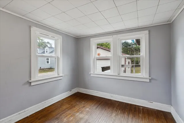 a view of an empty room with wooden floor and a window
