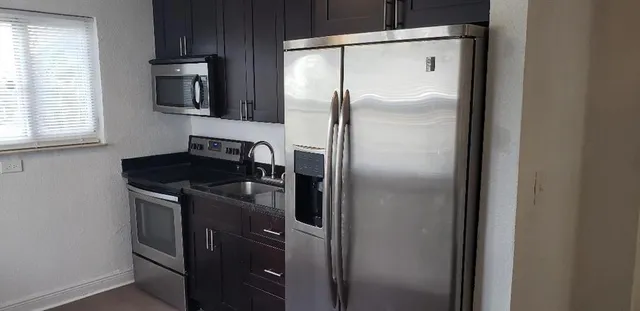 a close view of a refrigerator in kitchen and stainless steel appliances wooden floor
