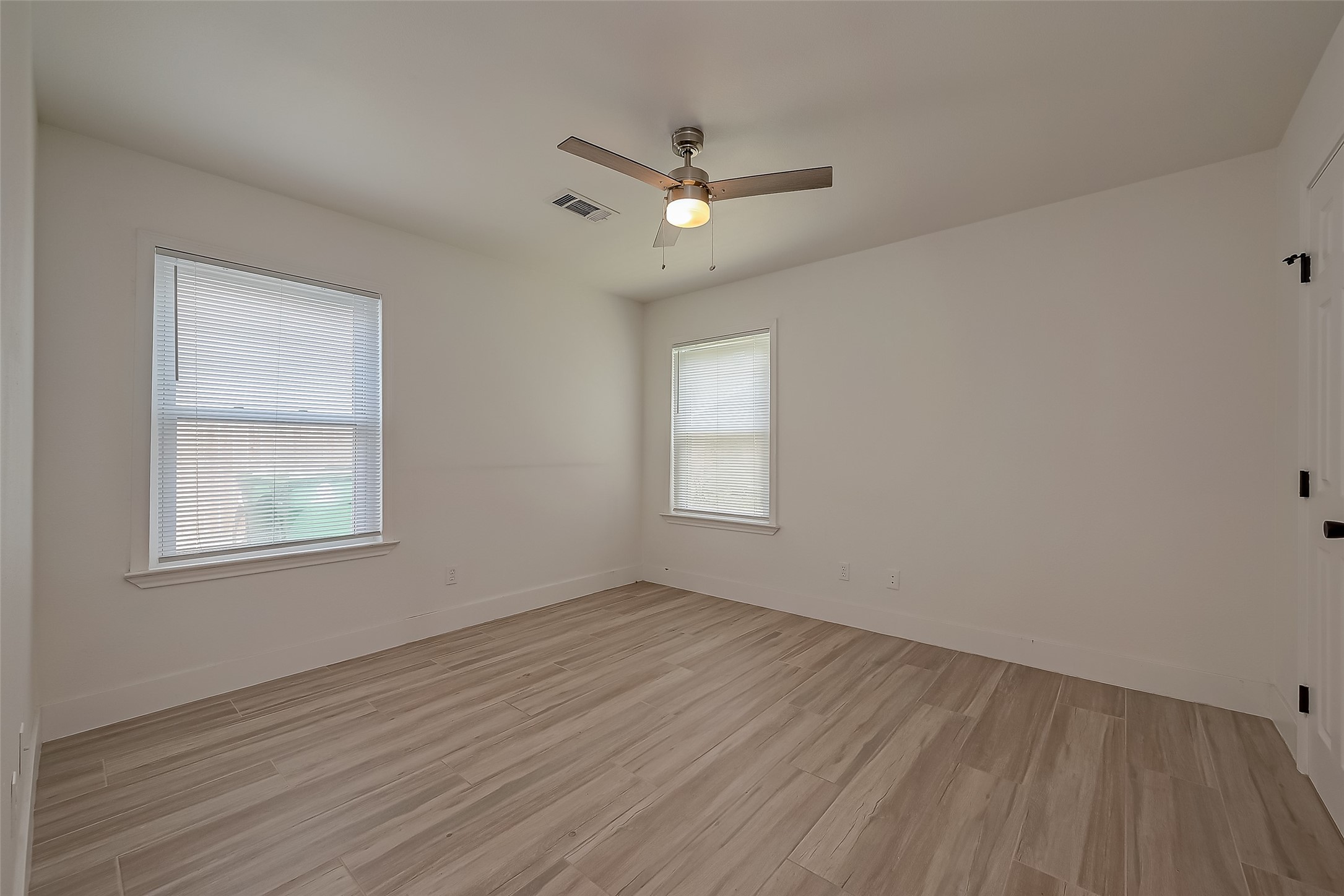 915 Adele Street Houston, TX 77009 - Photo 11 of 23 an empty room with wooden floor ceiling fan and windows