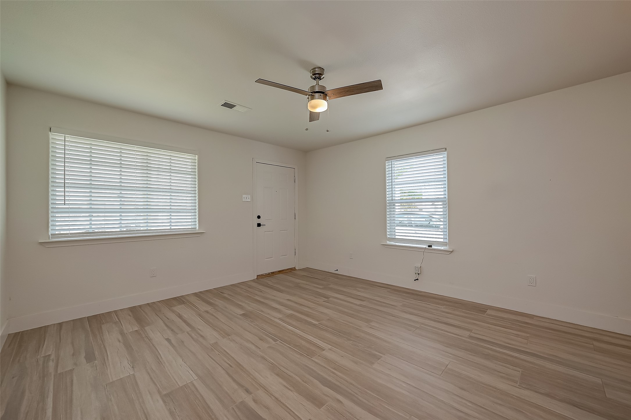 915 Adele Street Houston, TX 77009 - Photo 4 of 23 an empty room with wooden floor ceiling fan and windows