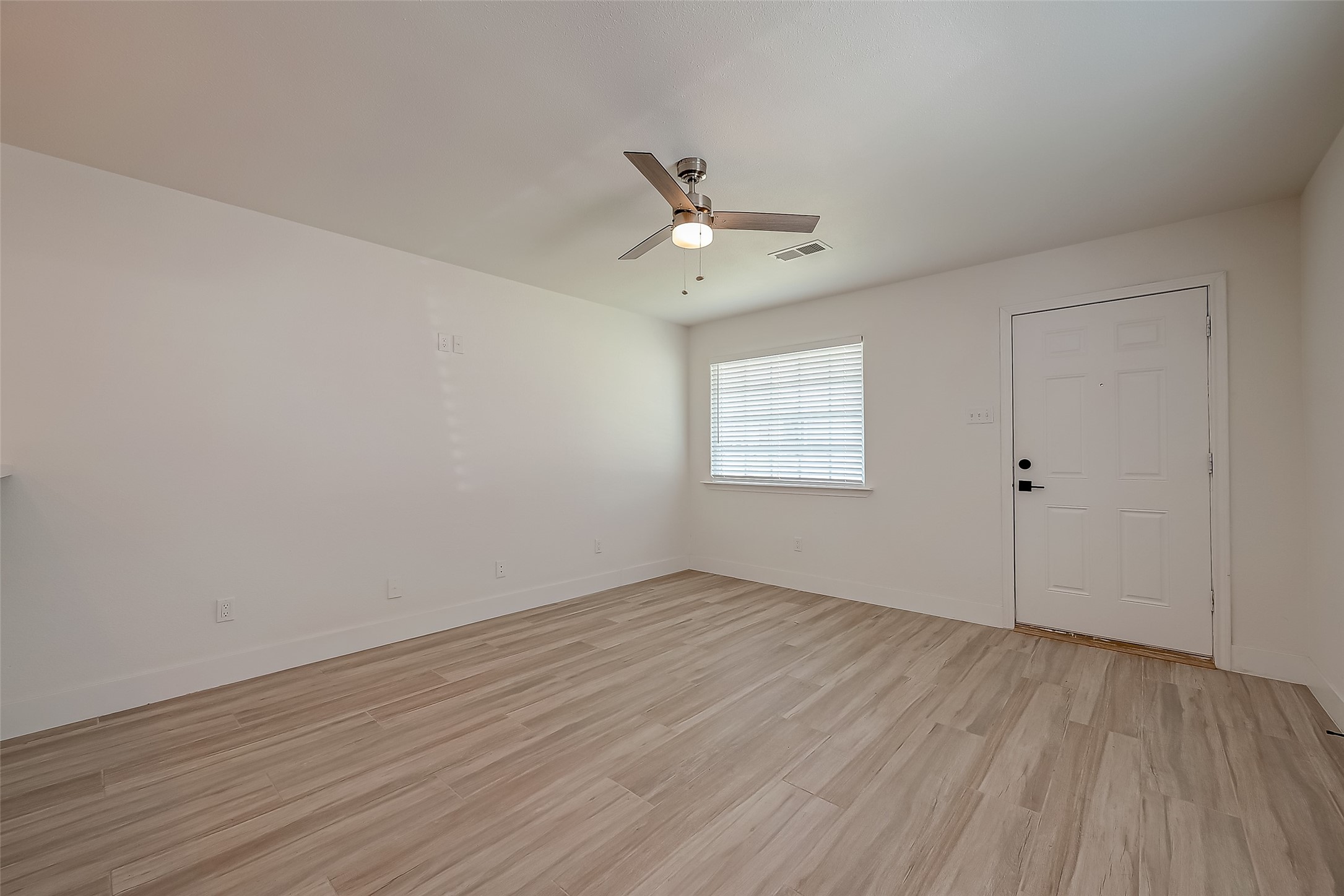 915 Adele Street Houston, TX 77009 - Photo 5 of 23 an empty room with wooden floor ceiling fan and windows