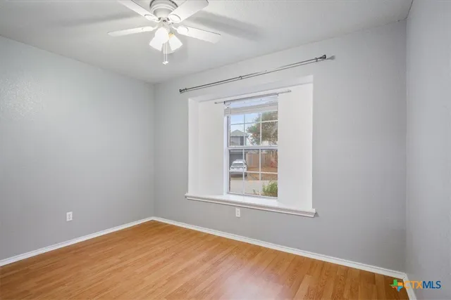 an empty room with a window and a fan