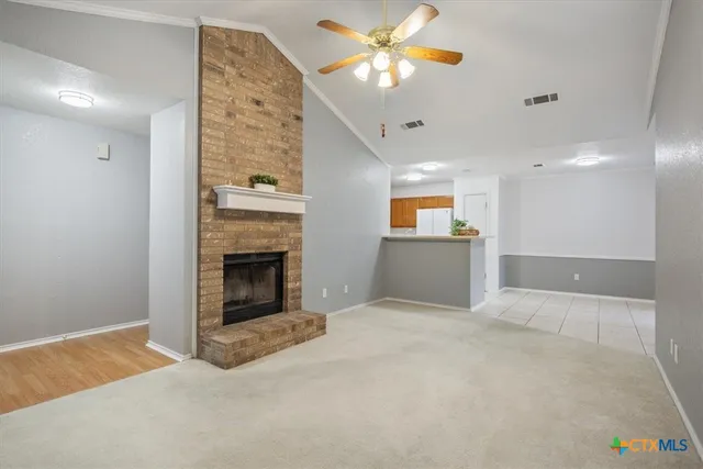 a view of an empty room with a fireplace and chandelier fan