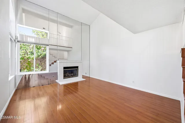 a view of empty room with wooden floor and fireplace