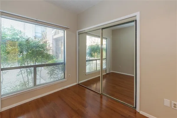 a view of an empty room with wooden floor and windows