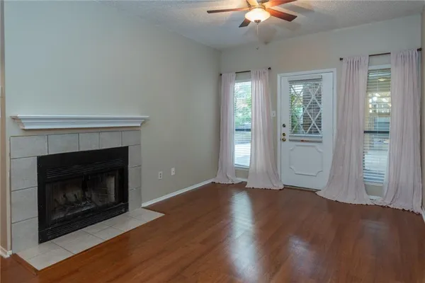 a view of an empty room with wooden floor fireplace and a window
